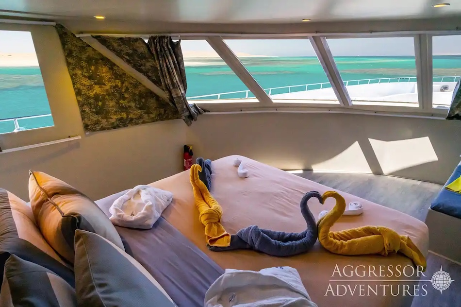 Elegante Kabine auf einer Yacht mit Blick auf das türkisfarbene Meer, Handtücher in Tierform.