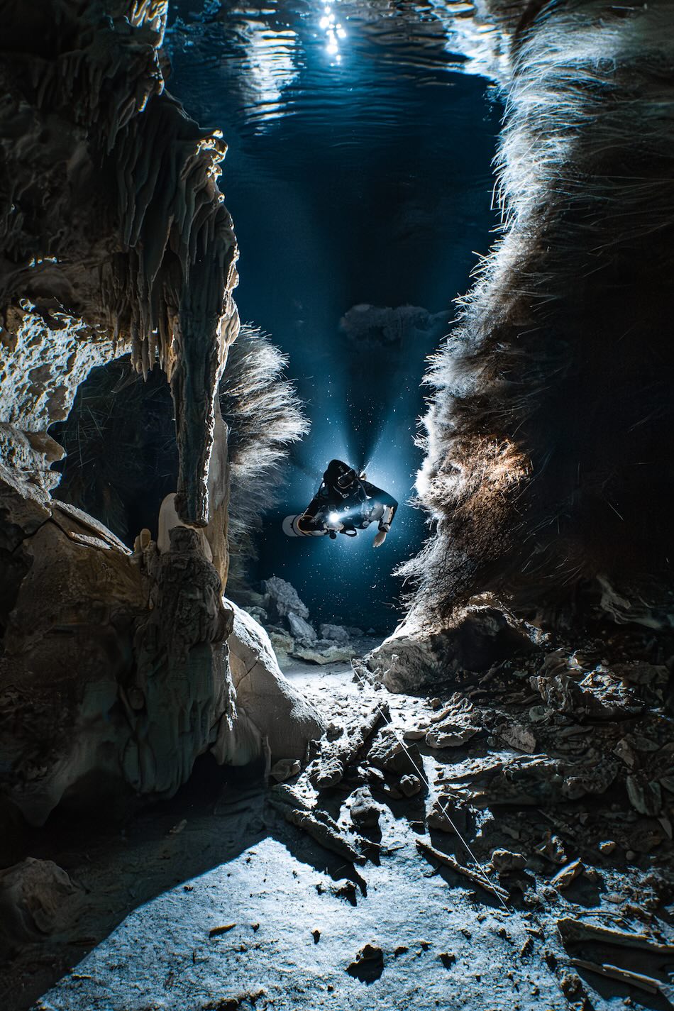 Tauchen in einer beleuchteten Unterwasserhöhle, die spektakuläre Formationen und einen abenteuerlustigen Entdecker enthüllt.