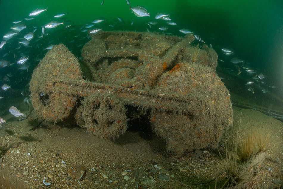 Ein Unterwassergerät, das mit Algen bedeckt ist und von Fischen bewohnt wird, zeugt von der ozeanischen Erkundung.